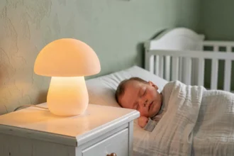 Veilleuse bébé personnalisée en silicone posée sur une table de nuit en bois blanc dans une chambre de bébé sage green